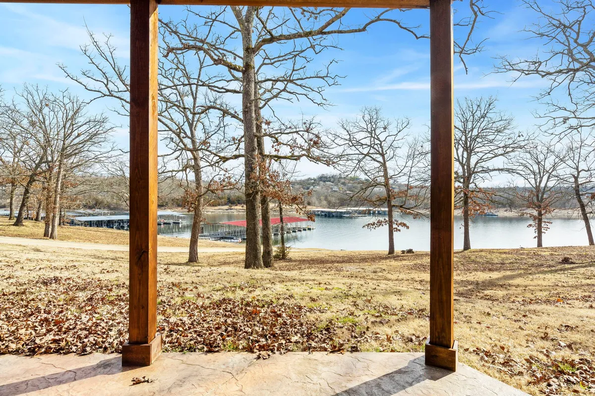 A tranquil view of the lake framed by tree branches and a patio structure, evoking the feeling of scenic walks and lakeside exploration.