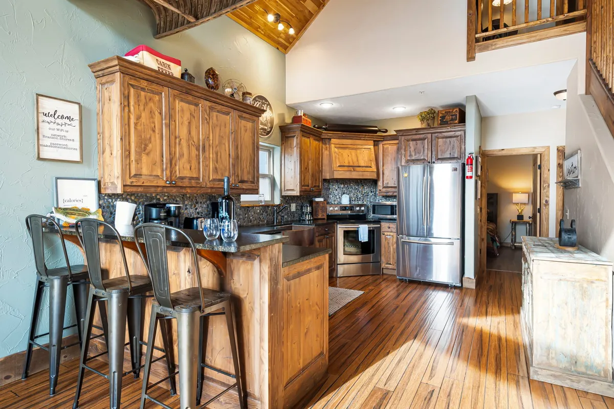 A modern, fully equipped kitchen with a central island and bar stools, stylish cabinetry, and stainless steel appliances. The open setup connects seamlessly with dining and living spaces, inviting culinary creativity and social interaction.