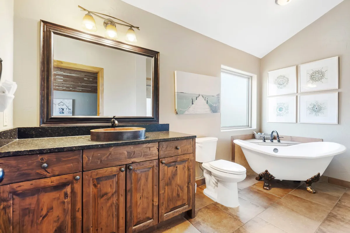 A serene bathroom with a freestanding bathtub, dark wood vanity, large mirror, and tasteful wall art. The natural light enhances the tranquil mood, perfect for unwinding after a day of adventure.