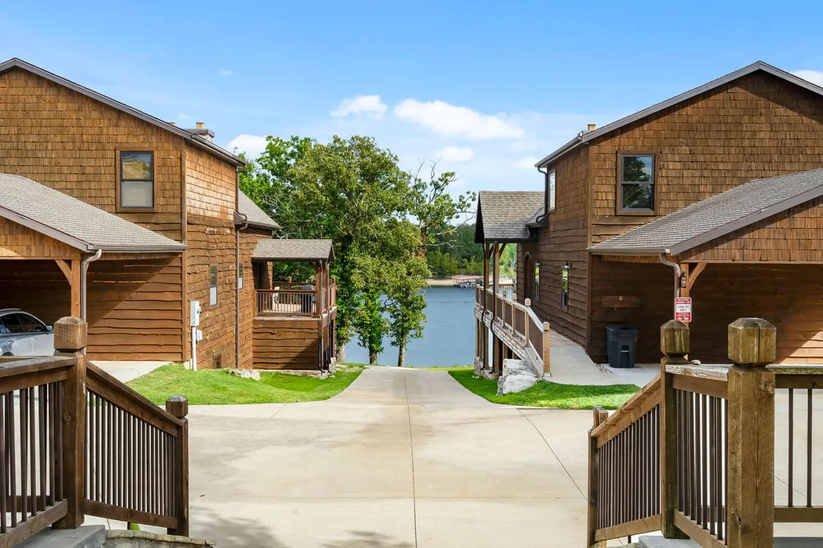 A peaceful scene featuring waterfront wooden cabins, a winding path leading toward the lake, lush greenery, and an inviting lake view. The image evokes a sense of connection to nature, with the proximity of the cabins to the water suggesting easy access to lakeside activities and relaxation.
